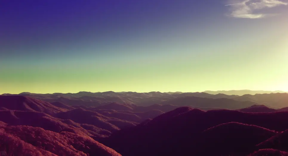 Mountain range along the blueridge parkway shot in infrared and converted to give the sky a blue/yellow gradient and the mountains deep reds.