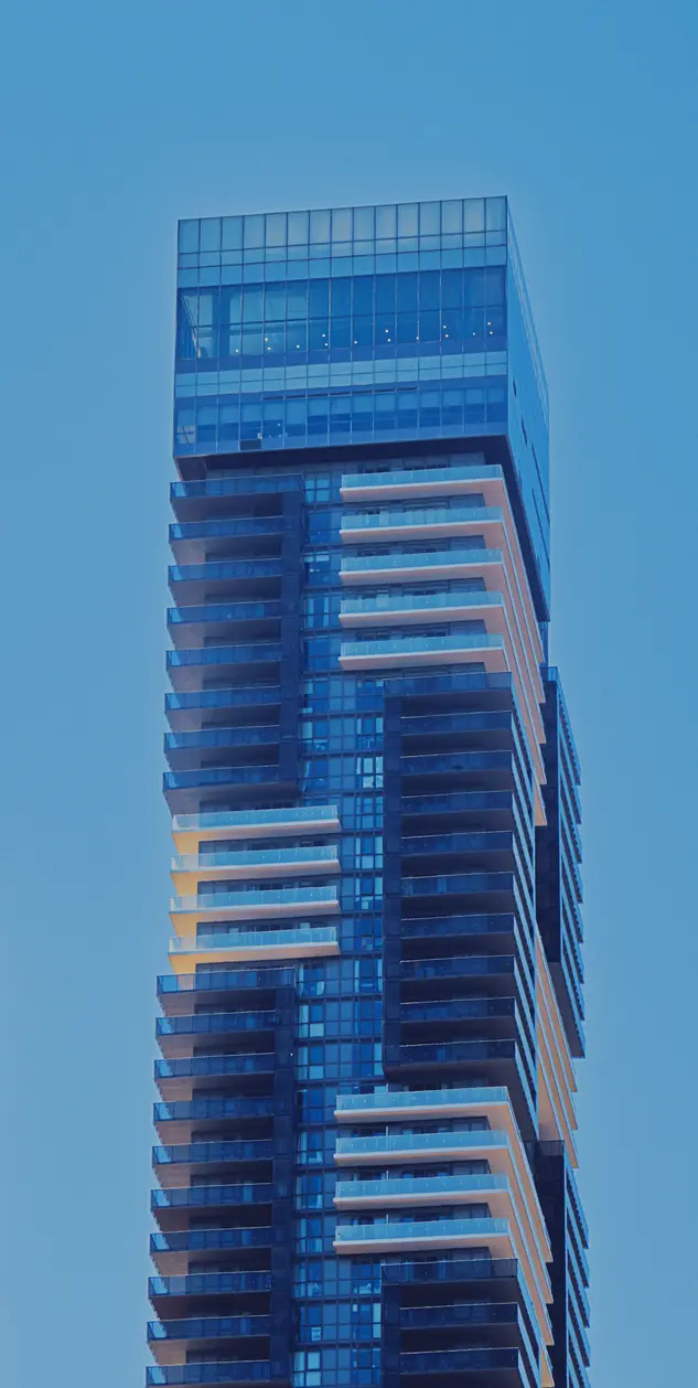 A large skyscrapper with a staggered black and white pattern extends up into the sky.