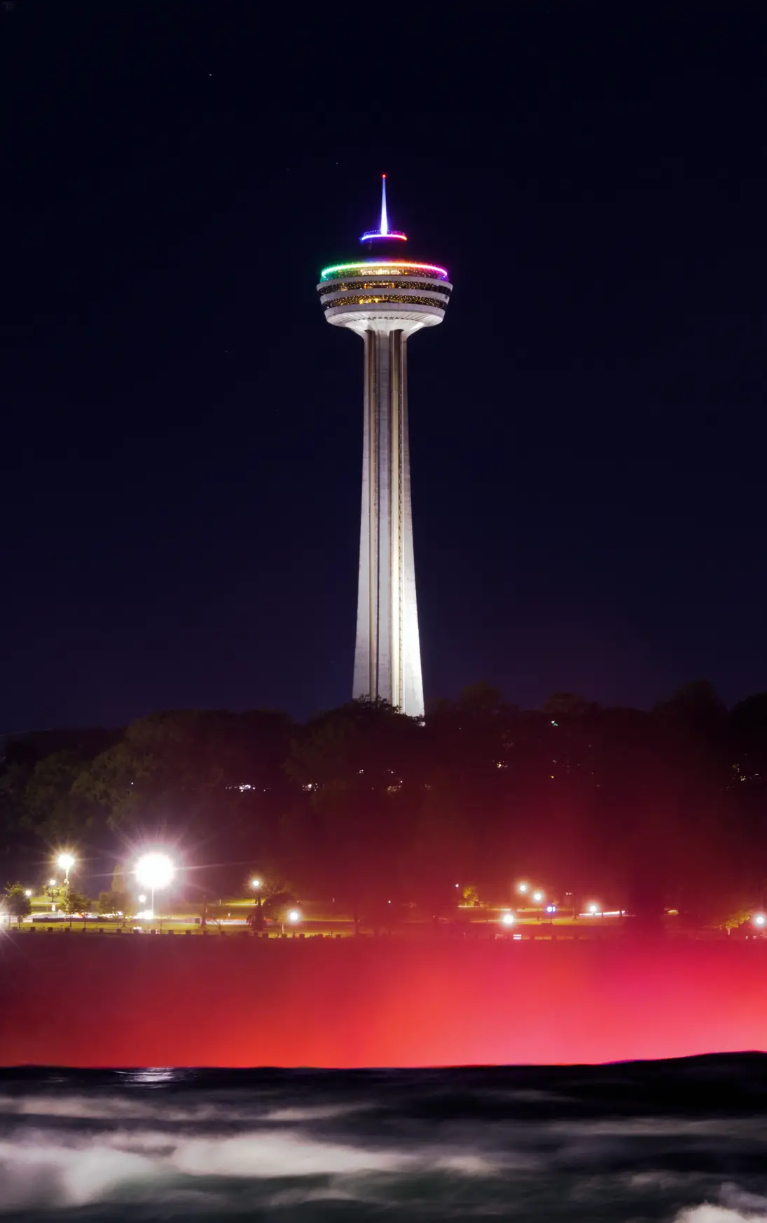 A needle structure at Niagara Falls at night lit up with various RGB colors.